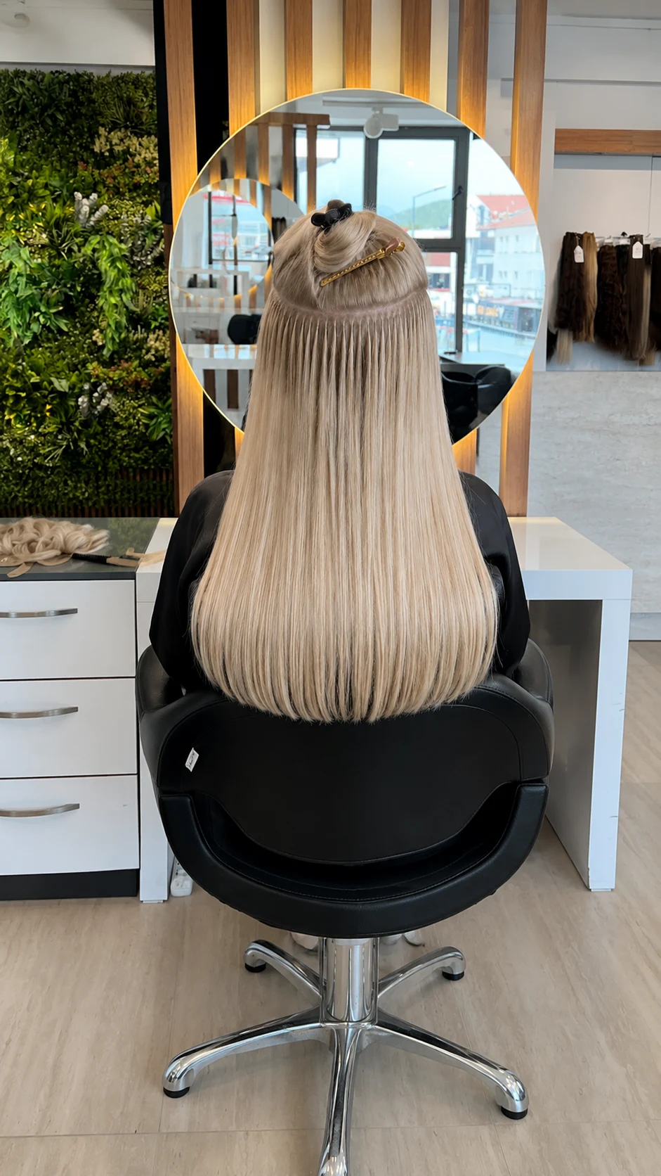 Professional stylist applying individual keratin hair extension strands with a fusion tool